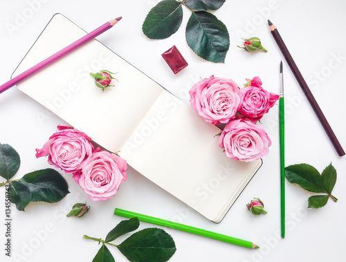 Colorful composition with sketchbook, roses and pencils. Flat lay