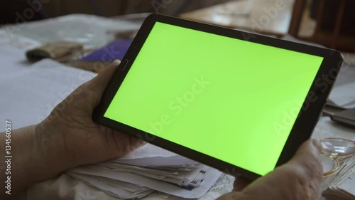 A blank tablet PC in landscape orientation with a green screenin hands. 4k photo