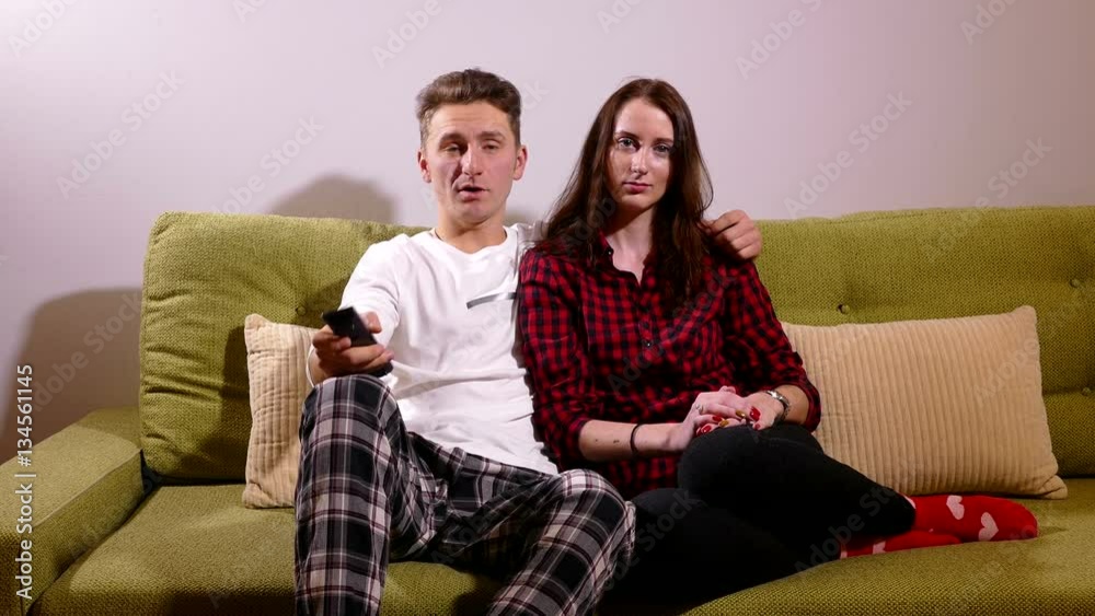 Young Couple Watching Tv on the sofa in the living room Young Couple Watching Tv on the sofa in the living room
