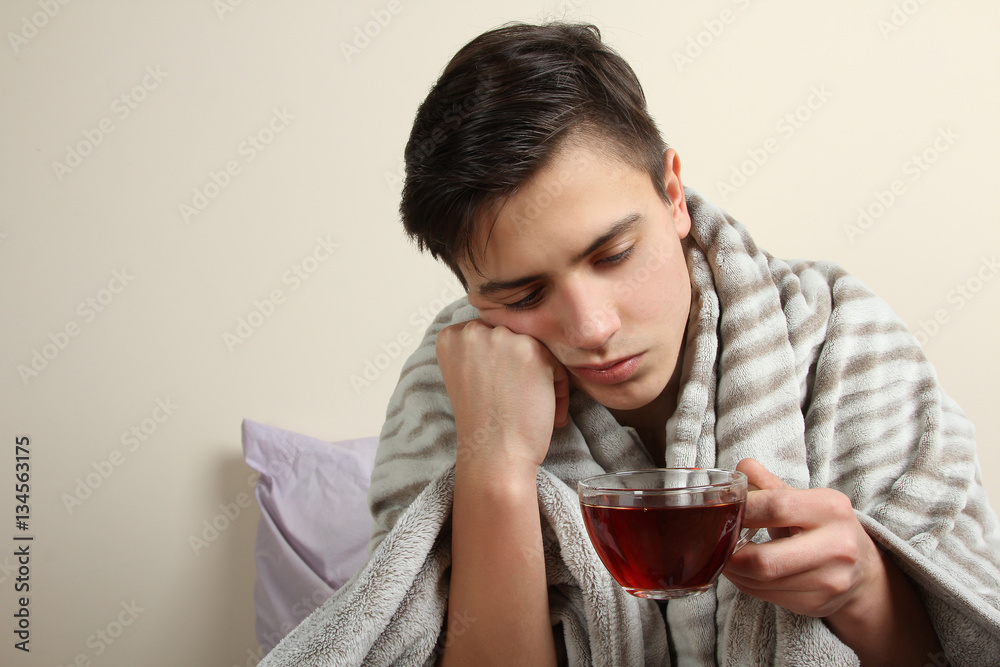 Wrapped in the warm blanket, sick, man drinking warm healing tea Wrapped in the warm blanket, sick, man drinking warm healing tea