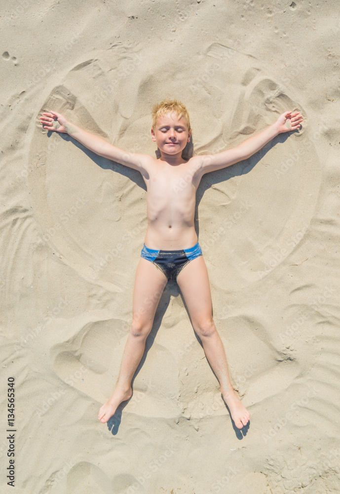 Fototapeta premium Boy making an angel on a sand