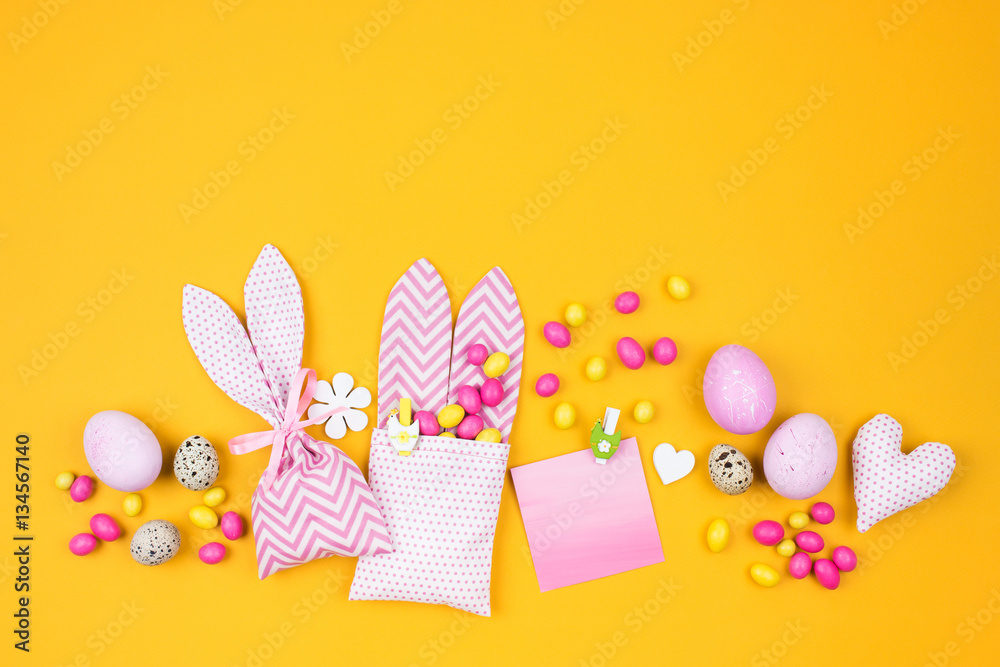 Easter decoration with eggs, bunny bag and candy on yellow background