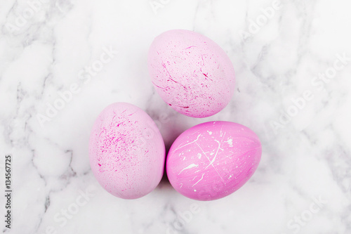 Minimal trendy pink easter eggs on marble background from above.