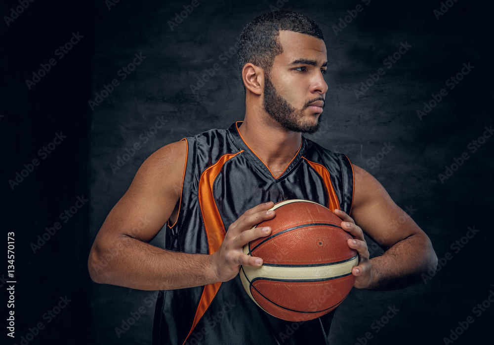 A black man holds a basket ball. A black man holds a basket ball.