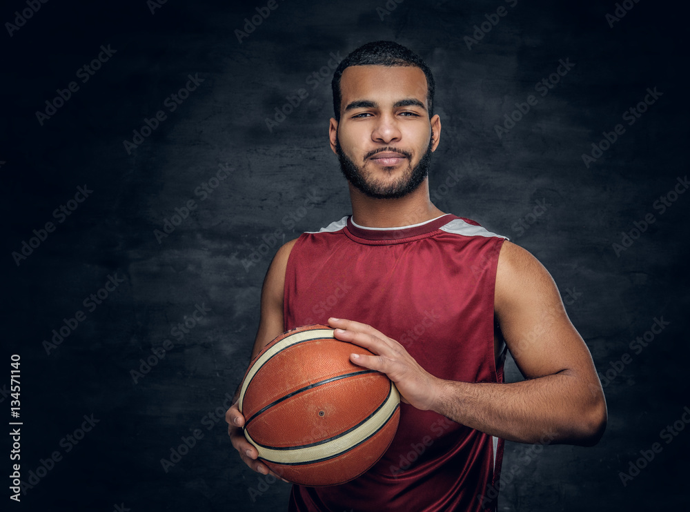 A black man holds a basket ball.