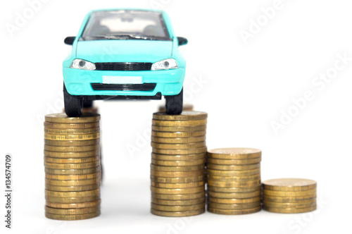 A blue car in top of stack of coins isolated on white background