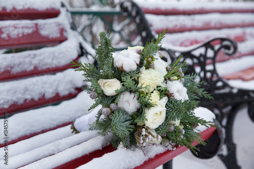 букет цветов с хвоей на скамье зимой