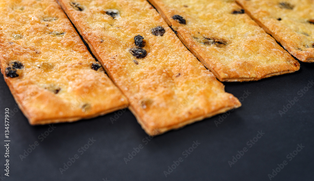Sweet cookies with raisins. Pastry strips on black background.
