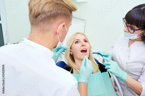 The patient is a girl with an open mouth at  dentist in  dental office.