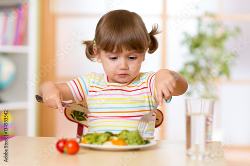 Cute little girl dining in kindergarten