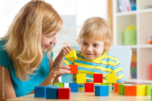 cute mother and kid boy play together with educational toys