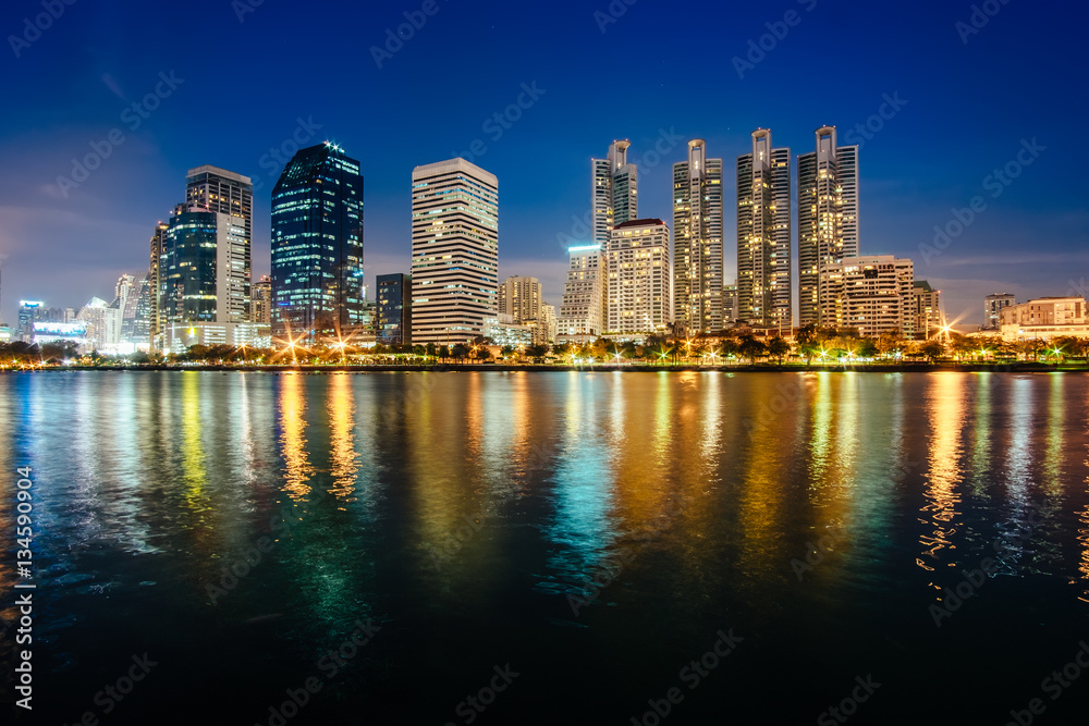 Asoke district with modern buildings in Bangkok, Thailand. Cityscape photography of Benchakitti Park at dusk. City downtown at twilight and night time in Asia