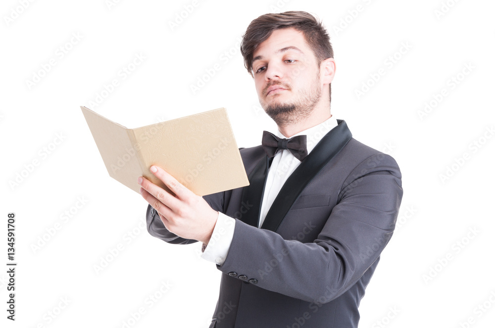 Handsome man wearing tuxedo and bowtie looking at catalogue Handsome man wearing tuxedo and bowtie looking at catalogue