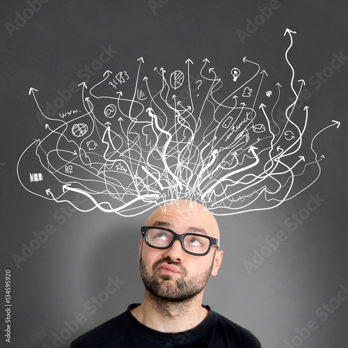 Tablou pe pânză Young attractive perplexed geek man with brainstormaing arrow ov