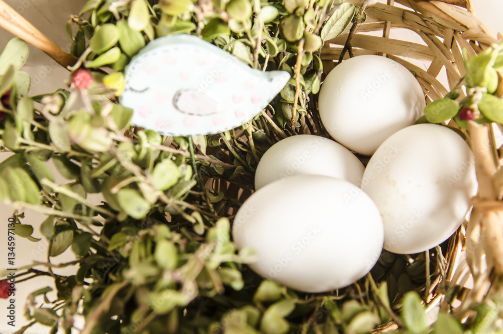 Beautiful white eggs in a basket with grass and birdie near basket.