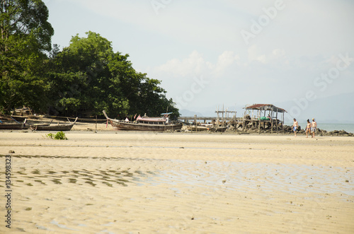 Thai people stop wooden fishing boat for repair and foreigner traveler walking on the beach