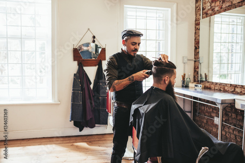 Male barber giving client haircut