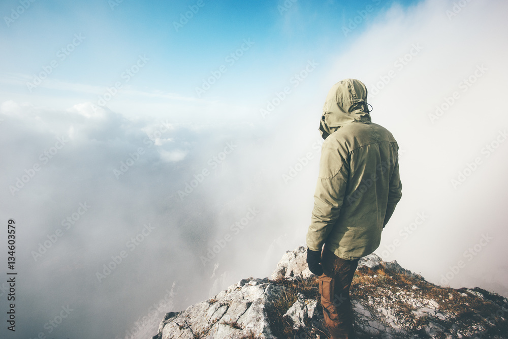 Traveler man alone on mountain summit over clouds Travel Lifestyle success concept adventure active vacations outdoor