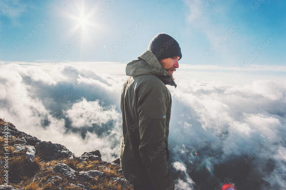 Man on mountain summit with sun over clouds Travel hiking Lifestyle success concept adventure active vacations outdoor