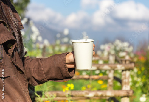 femals holding the hot of coffee in the garden with relaxed feel photo