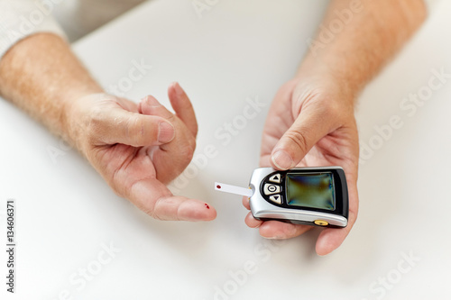 senior man with glucometer checking blood sugar