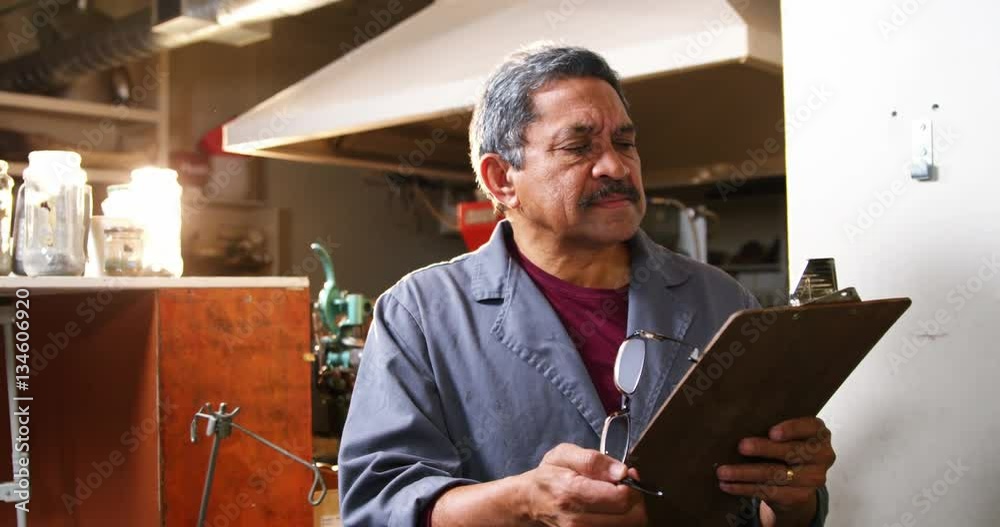 Slow motion of shoemaker reading clipboard in workshop 4k