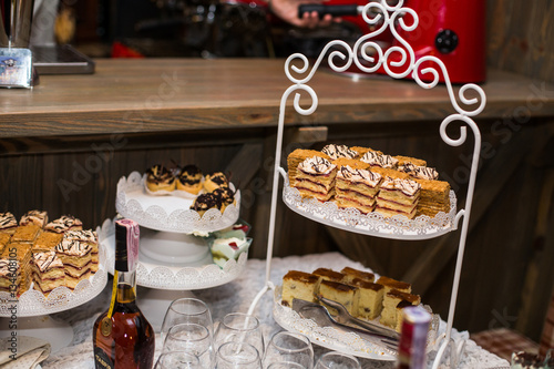 Different kinds of cakes stand on tired white dish on candy bar