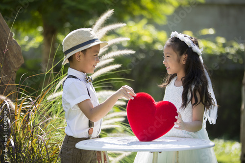 Little girl and boy holding red heart pillow concept for valenti photo