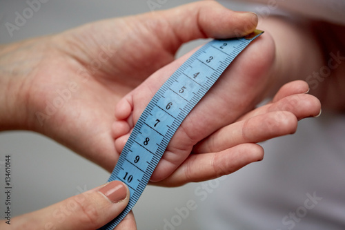 close up of hands with tape measuring baby foot