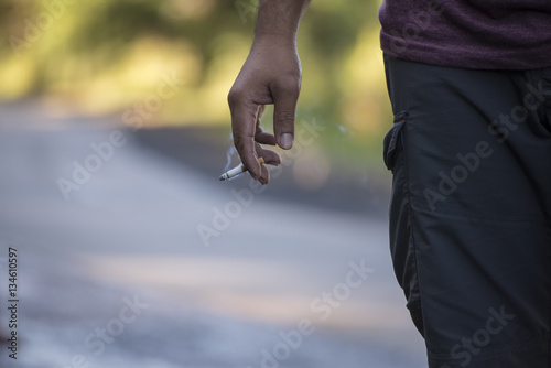 Closeup of a man holding a cigarette.