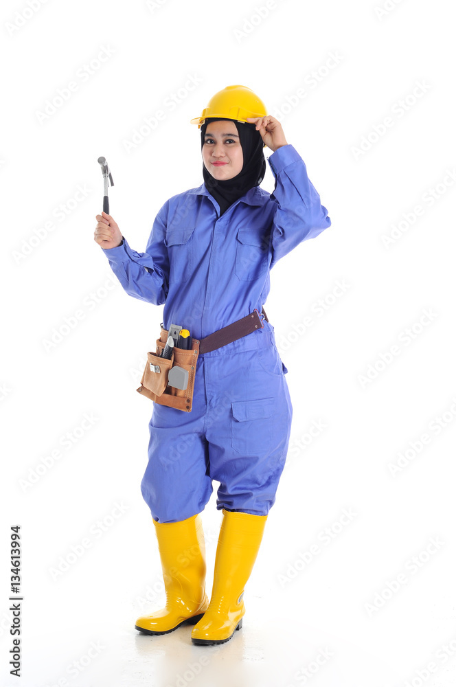 Construction worker wear yellow safety helmet in action while holding a hammer Construction worker wear yellow safety helmet in action while holding a hammer