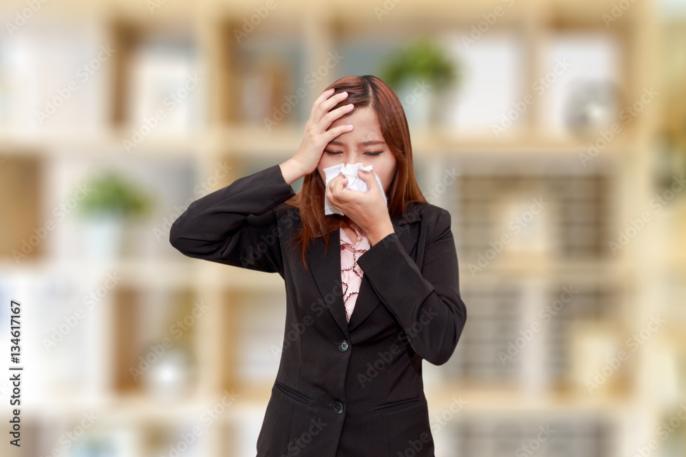 Businesswoman with allergy or cold sneezing into napkin Businesswoman with allergy or cold sneezing into napkin