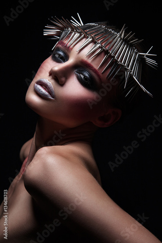 fashion beauty model with metallic headwear and shiny silver red makeup and blue eyes and red eyebrows on black background