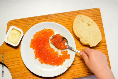 Child hand eating red caviar with spoon on white background. Close up image of delicacy food luxury lifestyle
