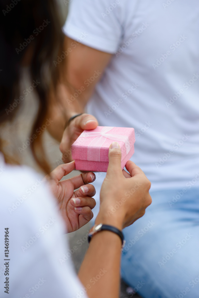 Detail of woman hands receiving a valentine's day or anniversary gift in a pink little box from her boyfriend. Detail of woman hands receiving a valentine's day or anniversary gift in a pink little box from her boyfriend.