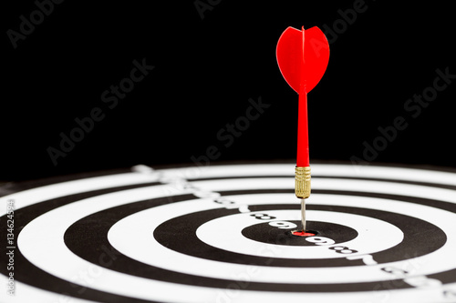 Target dart arrow hitting in the center of dartboard