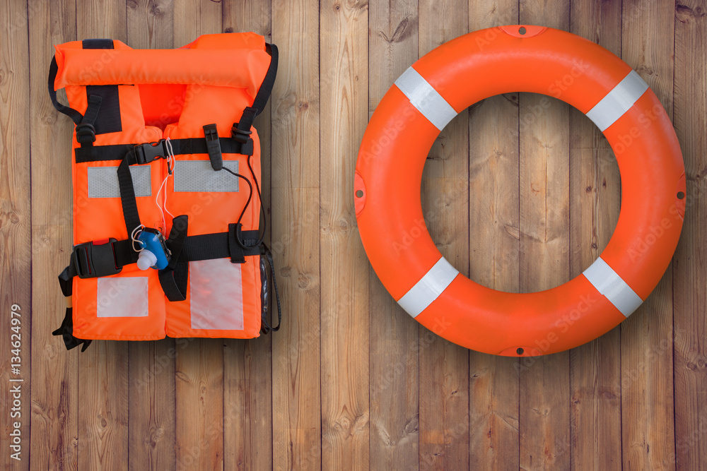 Life buoy and life jacket hanging on wooden wall for emergency response when people sinking to water almost place near pool and beach