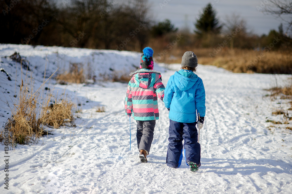 Two children of younger school age, boy and girl, walk on first snow.