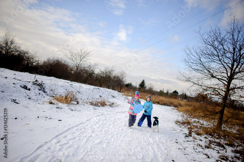 Two children, boy and girl, on winter walk with dog.
