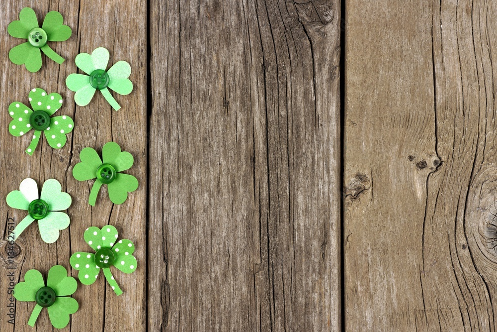 St Patricks Day side border of handmade paper shamrocks over a rustic wood background St Patricks Day side border of handmade paper shamrocks over a rustic wood background
