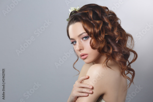 Beauty fashion portrait of a beautiful girl with a natural make-up and hairstyle curls isolated on a gray background.
