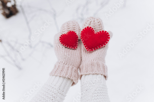 Girl in mittens holding heart on Valentine's day in winter outdoors