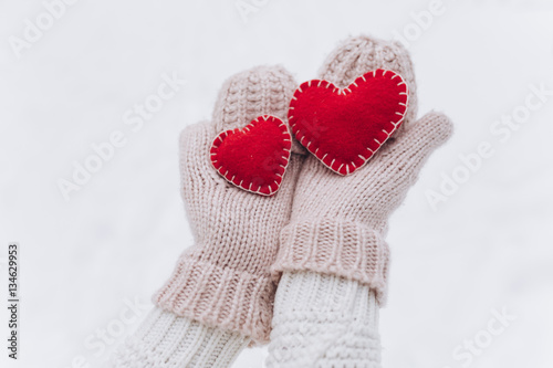 Girl in mittens holding heart on Valentine's day in winter outdoors