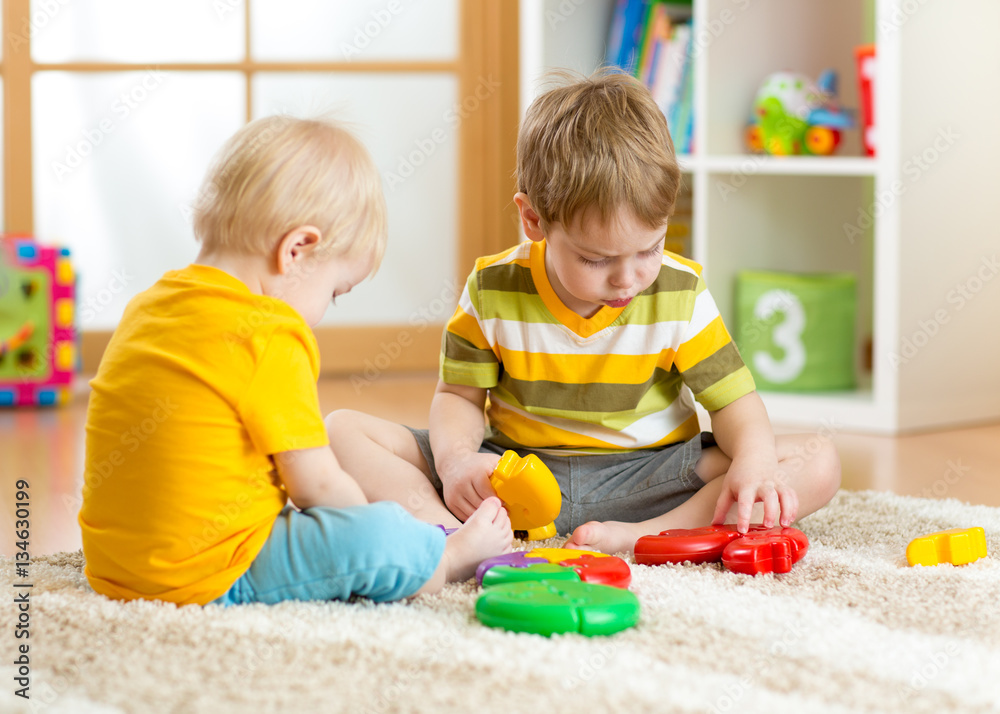 Kids little boy plays with a multi colored puzzle in nursery Kids little boy plays with a multi colored puzzle in nursery
