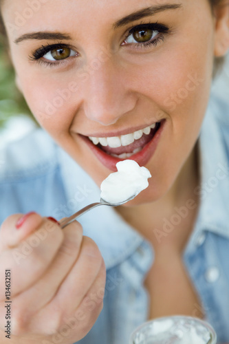Beautiful young woman eating yogurt at home.