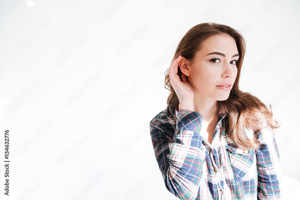 Fototapeta premium Pretty woman standing with hand at ear to hear better