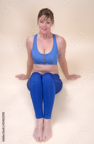 Φωτογραφία Woman wearing tights and a blue sports bra sitting on the floor
