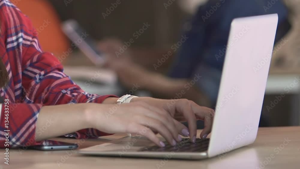 Female student working on laptop at campus library or chatting online in cafe Female student working on laptop at campus library or chatting online in cafe