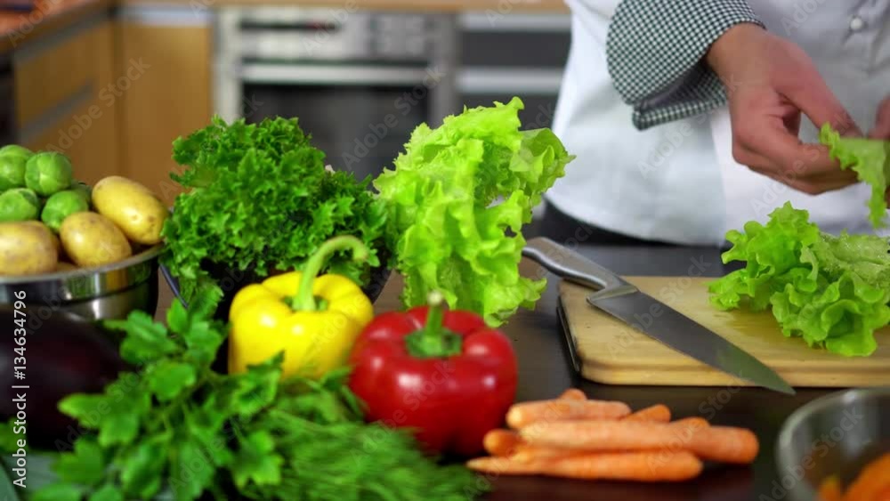 preparing salad - chef cutting lettuce on board in kitchen