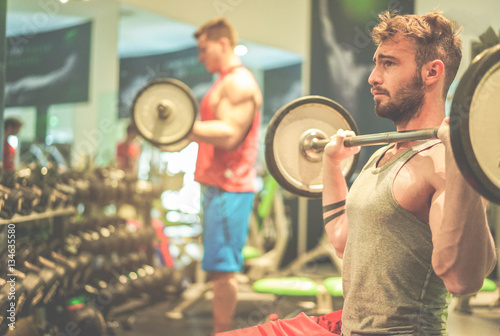 Athletes friends training with barbells inside american gym club